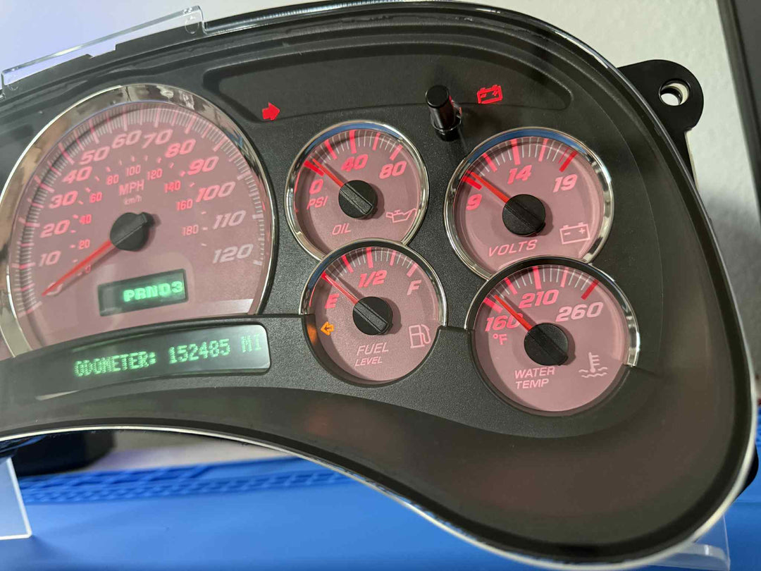 Custom pink Chevy Silverado instrument cluster with red gauge needles, backlit digital odometer, and chrome trim – showing speedometer, oil pressure, volts, fuel level, and water temperature gauges.
