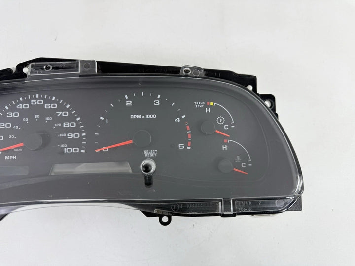 Close front view of a 2002–2004 Ford Super Duty instrument cluster showing tachometer, transmission temperature, coolant temperature, and other gauges.